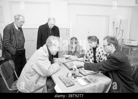 Kunstgutachten im Frans Hals Museum Haarlem Groot Heiligland Niederlande, Whizgle News, Dutch Desk, Niederlande, 1950 - 2000 am 24-04-1992. Dies sind die Elemente im Bild. In der Szene versammelt sich eine Gruppe von sechs Personen um einen Tisch, der mit verschiedenen Materialien und Werkzeugen bedeckt zu sein scheint, was auf eine gemeinsame oder durchdachte Aktivität hindeutet. Die Leute unterhalten sich mit drei Personen, die am Tisch sitzen und drei in der Nähe stehen. Die sitzenden Figuren zeigen unterschiedliche Ausdrucksformen der Konzentration; ein Mann, der sich durch Brille und weißes h auszeichnet Stockfoto