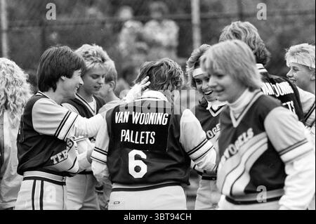 Terrasvogels - HCAW Softball, Whizgle News, Dutch Desk, Niederlande, 1950 - 2000 am 01-08-1987. Diese Themen werden in der Abbildung angezeigt. Die Szene fängt einen lebendigen Sportereignis ein, der von einem Gefühl der Kameradschaft und des Feierns geprägt ist. Eine Gruppe von acht Einzelpersonen, die in passenden Mannschaftstrikots gekleidet sind, steht eng zusammen und strahlt Spannung und Energie aus. Die Trikots sind überwiegend dunkel, mit hellen Akzenten, die sie vor dem Hintergrund eines grasbewachsenen Feldes auffallen lassen. Die Menschen haben unterschiedliche Frisuren und Farben, was zu einer dynamischen visuellen Anziehungskraft beiträgt. Einige haben lockiges Haar, andere Stockfoto
