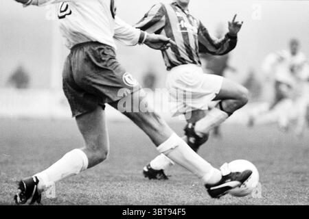 Fußball: Stormvogels - OSV IJmuiden IJmuiden the Netherlands, Whizgle News, Dutch Desk, Niederlande, 1950 - 2000 am 01-11-1997. Dies sind die Elemente im Bild. Die Szene fängt einen dynamischen Moment in einem Fußballspiel ein und konzentriert sich dabei auf die Bewegungen der Spieler. Zwei Athleten stehen im Vordergrund, die beide an der Aktion beteiligt sind. Ein Spieler, der ein weißes Trikot mit der Zahl „5“ trägt, ist bereit, den Ball zu kicken. Sein Bein wird gespannt und betont die Kraft und Beweglichkeit, die der Sport erfordert. Der andere Spieler, der in einem gestreiften Trikot gekleidet ist, ist in einer solchen Wa positioniert Stockfoto
