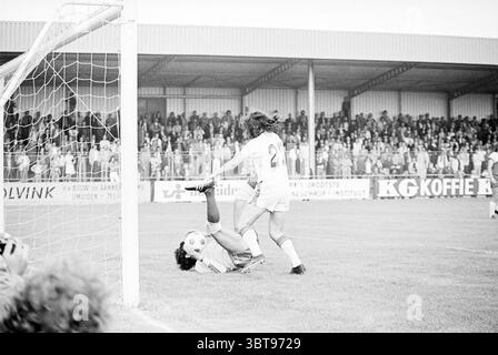 Fußballspiele inklusive. Haarlem - DCO - Telstar Football Haarlem, Whizgle News, Dutch Desk, Niederlande, 1950 - 2000 am 20-07-1975. Diese Themen sind in der Abbildung dargestellt. In einer energiegeladenen Outdoor-Sportarena fängt die Szene einen Moment intensiver Action auf einem Fußballfeld ein. Der grasbewachsene Platz ist lebendig und gepflegt und steht im Kontrast zum Schmutz und Schlamm, der an den Torpfosten gesammelt wurde. Ein Spieler, der in einer weißen Uniform mit einer deutlich sichtbaren Zahl auf dem Rücken gekleidet ist, ist mitten im Geschehen und führt eine markante Bewegung in Richtung des Balls aus. Ein anderer Spieler, der die Uniform eines Torwarts trägt – in der Regel eine helle Farbe – h Stockfoto