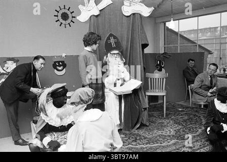 Saint Nicholas at Stork St. Nicholas Sinterklaas, Whizgle News, Dutch Desk, Niederlande, 1950 - 2000 am 04-12-1968. Dies sind die Elemente im Bild. In einem lebhaften Innenbereich ist eine kleine Bühne mit fröhlichen Dekorationen wie verspielten Sonnen- und Smiley-Motiven an der Wand geschmückt. Die Atmosphäre wirkt festlich und verspielt, was auf eine besondere Veranstaltung hindeutet, die möglicherweise mit einer Feier oder Vorstellung zusammenhängt. In der Mitte sitzt eine als Sinterklaas gekleidete Figur, komplett mit einem hohen, spitzen Hut und einem langen Gewand, auf einem Stuhl und hält ein Buch offen. Der Ausdruck des Charakters vermittelt eine Mischung aus AUT Stockfoto