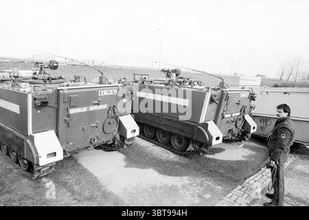 Panzerwagen auf Schiphol Zufahrtsstraßen Schiphol Schiphol, Whizgle News, Dutch Desk, Niederlande, 1950 - 2000 am 08-03-1990. Das Bild enthält diese Themen. Die Szene zeigt eine Gruppe von Militärfahrzeugen, die auf einem zerklüfteten Gelände geparkt sind, gekennzeichnet durch Kies und Grasflecken. Drei gepanzerte Personentransporter sind eng aneinander angeordnet, deren metallische Oberflächen eine matte Oberfläche mit gedämpften Grau- und Olivgrün-Tönen aufweisen. Diese Fahrzeuge sind oben mit turmähnlichen Strukturen ausgestattet, was auf Einsatzbereitschaft hinweist, während die Schienen zeigen, dass sie in rauem Untergrund navigieren können Stockfoto