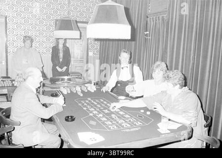 Golden Ten Club Haarlem Glücksspiele und Spielzeuge Haarlem the Netherlands, Whizgle News, Dutch Desk, Niederlande, 1950 - 2000 am 16-09-1984. Das Bild enthält diese Themen. Die Szene fängt eine lebhafte Atmosphäre ein, die typisch für ein Kasino ist. In der Mitte befindet sich ein großer, ovaler Roulette-Tisch mit einer Vielzahl von Chips in unterschiedlichen Farben, in der Mitte befindet sich ein kleines Rad. Um den Tisch herum spielen vier Personen mit einer Mischung aus Konzentration und Spannung. Nach links lehnt sich ein Mann mit einem ordentlich geschnittenen Schnurrbart und einem Anzug leicht nach vorne, sein Blick ist fest auf t gerichtet Stockfoto
