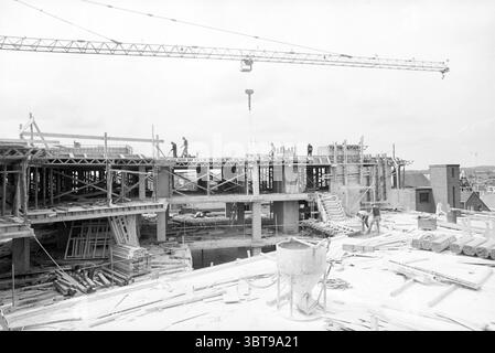 Bautätigkeiten Brinkmann Complex Construction Baugruben Arbeit Haarlem Grote Markt Niederlande, Whizgle News, Dutch Desk, Niederlande, 1950 - 2000 am 19-08-1980. Diese Themen sind in der Abbildung dargestellt. Die Szene zeigt eine aktive Baustelle, auf der viele Arbeiter mit verschiedenen Aufgaben beschäftigt sind. Es sind mehrere Personen sichtbar, die sich in der Skelettstruktur eines teilweise gebauten Gebäudes bewegen, jedes mit Schutzkleidung wie Schutzhelmen und reflektierenden Westen verkleidet, was die Sicherheitsprotokolle der Umwelt unterstreicht. Die Baustelle ist überfüllt mit Materialien und Werkzeugen. Holz Stockfoto