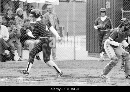 Softball Terrasvogels - Sparks, Whizgle News, Dutch Desk, Niederlande, 1950 - 2000 am 18-06-1993. Diese Themen werden in der Abbildung angezeigt. In der Szene entfaltet sich ein dynamischer Moment auf einem Baseballfeld. Ein Spieler in einer gestreiften schwarz-weißen Uniform stürzt auf die Heimplatte, sein Körper ist entschlossen nach vorne geneigt. Die Uniform hat eine markante Zahl auf der Rückseite, und die Kappe ist nach unten gezogen, wodurch ihr Gesicht teilweise verdeckt wird. Ihre Stollen werfen beim Sprinten eine kleine Staubwolke aus dem Innenfeld auf. Auf der rechten Seite ist ein Fänger in Schutzkleidung und Helm vorbereitet und fokussiert. Seine Pos. Stockfoto