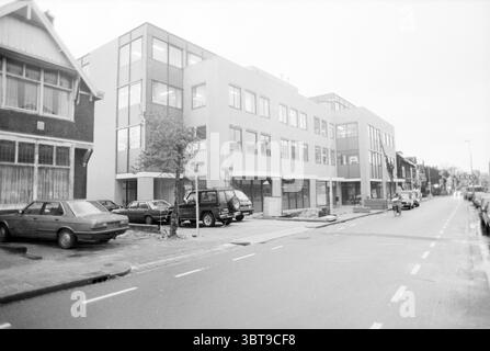 Erw. Riag beverwijk Exterior Beverwijk the Netherlands, Whizgle News, Dutch Desk, Niederlande, 1950 - 2000 am 06-01-1988. Das Bild enthält diese Themen. Die Szene zeigt eine urbane Straßenlandschaft, die von einer Mischung aus architektonischen Stilen geprägt ist. Auf der einen Seite steht ein modernes mehrstöckiges Gebäude mit einer Mischung aus großen Fenstern und minimalistischen Designelementen in weiß- und Hellgrau-Tönen. Es steht im Kontrast zu den älteren, traditionellen Gebäuden, die sich daneben durch dunkles Ziegelwerk und geneigte Dächer auszeichnen, was auf einen historischen Charme hindeutet. Im Vordergrund ein schmales Stockfoto
