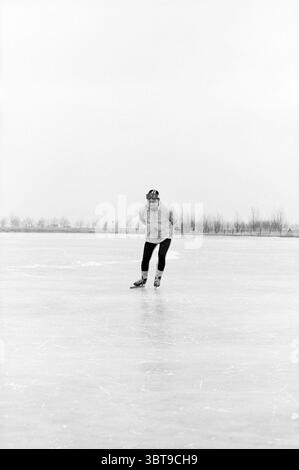 Jac. Sour Beer on Skates Skating, Whizgle News, Dutch Desk, Niederlande, 1950 - 2000 am 20-02-1985. Diese Themen sind in der Abbildung dargestellt. Eine einsame Figur gleitet anmutig über eine glatte, gefrorene Oberfläche, das Eis reflektiert einen gedämpften, silbernen Glanz. Die Person trägt eine helle Jacke, die Wärme gegen die kühle Atmosphäre suggeriert. Die Beine sind mit eng anliegenden schwarzen Hosen verziert, die auf Geschwindigkeit und Agilität auf dem Eis zugeschnitten sind. Der einzelne lehnt sich leicht nach vorne und strahlt ein Gefühl von Konzentration und Eleganz aus, während er Linien in das Eis schneidet und eine zarte Spur hinterlässt. A f Stockfoto