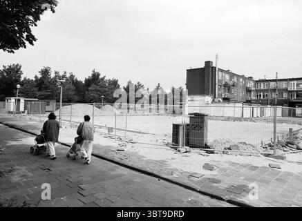 Übersicht über Bauland Prins Bernhardlaan Beatrixplein Baustellen Haarlem Prinses Beatrixplein Niederlande, Whizgle News, Dutch Desk, Niederlande, 1950 - 2000 am 23-06-1989. Dies sind die Themen im Bild. Die Szene zeigt eine raue urbane Landschaft mit zwei Figuren, die Seite an Seite auf einem Kopfsteinpflasterweg laufen. Beide tragen hellere Kleidung, was vielleicht auf einen lässigen Ausflug hinweist. Jede Person schiebt einen Kinderwagen, was darauf hindeutet, dass der Schwerpunkt auf Familie oder Kinderbetreuung liegt. Um sie herum befindet sich eine karge Baustelle, die von Erdhügeln, St. Stockfoto
