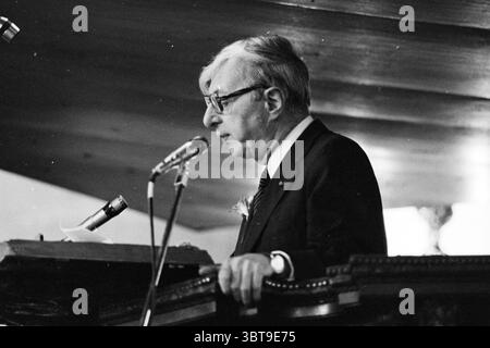 Fa. Enschede in Grote Kerk 275 Jahre Existenz. Rede von Jelle Zijlstra Präsidentin der de Nederlandsche Bank, Whizgle News, Dutch Desk, Niederlande, 1950 - 2000 am 21. Juni 1978. Dies sind die Elemente im Bild. Die Szene zeigt einen älteren Mann, der bei einer formellen Veranstaltung spricht, hinter einem hölzernen Podium. Sein Verhalten deutet darauf hin, dass er mit Ernsthaftigkeit und Autorität ein Publikum anspricht. Der Mann trägt einen dunklen Anzug, gepaart mit einer runden Brille, die ihm eine intellektuelle Präsenz verleiht. Er hat sauber gekämmte graue Haare, die sein Gesicht umrahmen. Die Einstellung enthält warme, stummgeschaltete Töne, die durch t verstärkt werden Stockfoto