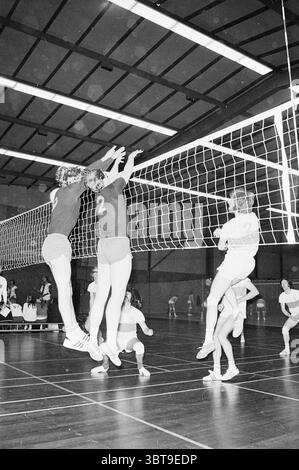 Alliance - NCIJ IJmuiden Volleyball, Whizgle News, Dutch Desk, Niederlande, 1950 - 2000 am 15-05-1973. Dies sind die Themen im Bild. Die Szene fängt einen intensiven Moment in einem Volleyballspiel ein, das in einer Turnhalle stattfindet. Zwei Athleten in passenden dunklen Trikots und Shorts springen in die Luft, ihre Arme reichen hoch über dem Volleyballnetz in einem Defensivmanöver. Die Trikots stehen im Kontrast zur Monotonie des dunklen Fitnessstudios und stehen im hellen weiß des Netzes. Einer der Spieler scheint heftige Entschlossenheit zu zeigen, sein fokussierter Ausdruck ist sichtbar, wenn er sich ausdehnt Stockfoto
