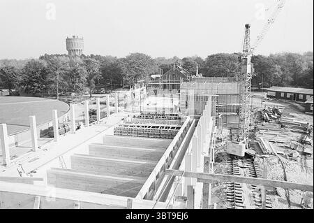 Wasserpfeife Haarlem Exterior Water Pipe, Whizgle News, Dutch Desk, Niederlande, 1950 - 2000 am 09-10-1969. Dies sind die Elemente im Bild. Die Szene zeigt eine weitläufige Baustelle, die eine Mischung aus Industrieaktivitäten und Rohstoffen zeigt. Im Vordergrund stehen mehrere große Betonbalken aufrecht, die Teil eines tragenden Rahmens sind, während um sie ein Holzgerüst montiert ist, was auf die aufkeimende Konstruktion eines Gebäudes hindeutet. Auf der rechten Seite erhebt sich ein hoher Kran über dem Gelände, dessen Metallarm nach außen zeigt, dass er sich aktiv bewegt, da er wahrscheinlich schwer hebt Stockfoto