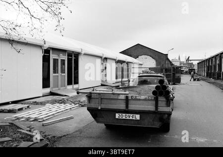 Bau einer provisorischen Kantine für Nedtrain Haarlem, Niederlande, Whizgle News, Dutch Desk, Niederlande, 1950 - 2000 am 14.01.2003. Dies sind die Elemente im Bild. Die Szene zeigt einen Baubereich, der durch eine monochromatische Palette charakterisiert ist, was auf einen bewölkten oder bewölkten Tag hindeutet, der ein gedämpftes Licht über die Umgebung wirft. Auf der linken Seite ist ein provisorisches Gebäude mit weißem Äußeren zu sehen, dessen große Glastüren einen gedämpften, grauen Himmel reflektieren. Das Gebäude wirkt funktional und neu und steht im Kontrast zur Umgebung. Im Vordergrund ein Nutzfahrzeug Stockfoto