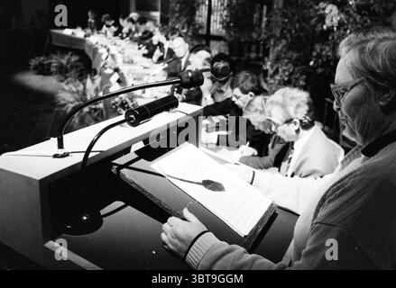 Anhörung des Aktionsplans Schiphol Expansion in Haarlemmermeer Town Hall Hoofddorp Raadhuisplein the Netherlands, Whizgle News, Dutch Desk, Niederlande, 1950 - 2000 am 22-01-1991. Die Abbildung zeigt diese Themen. Die Szene fängt ein formelles Treffen in einem gut beleuchteten Innenbereich ein. Im Vordergrund steht ein Lautsprecher auf einem Podium mit zwei Mikrofonen. Der Lautsprecher ist in einen hellen Pullover gekleidet, dessen Fokus auf die vor ihm platzierten Noten gerichtet ist. Das Podium besteht aus poliertem Holz, und die Ader des Holzes glänzt dezent unter den Bühnenlichtern. Im Hintergrund ein Bedienfeld Stockfoto