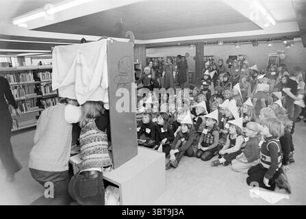 Kinderparty H'lem Bibliothek Kinder Kinder Kinderheime Kinderparty Kinder, Whizgle News, Dutch Desk, Niederlande, 1950 - 2000 am 22-10-1975. Dies sind die Themen im Bild. Die Szene fängt ein lebhaftes Treffen in einem geräumigen Innenbereich ein, wahrscheinlich in einer Bibliothek oder einem Gemeindezentrum. Im Vordergrund sieht sich eine Gruppe von Kindern eifrig eine Vorstellung oder Präsentation an. Sie sitzen im Kreuz auf dem Boden, einige lächeln, während andere von dem sich abzeichnenden Ereignis fasziniert wirken. Auf den Köpfen sind bunte Hüte zu sehen, die der Szene eine verspielte Ästhetik verleihen. In der Mitte Stockfoto