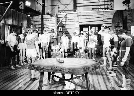 Amsterdam Aufnahmen von Co de Boswachter Amsterdam the Netherlands, Whizgle News, Dutch Desk, Niederlande, 1950 - 2000 am 12-01-1991. Das Bild enthält diese Themen. Die Szene spielt drinnen und erinnert an eine rustikale Holzstruktur mit rauen Wänden, die eine traditionelle oder Vintage-Ästhetik vermitteln. Der Boden besteht aus Holzdielen, die der Umgebung Wärme und Textur verleihen. In der Mitte steht ein großer, runder Tisch mit dicker, knorriger Kante im Vordergrund, der auf einen Gemeinschaftsraum für Versammlungen oder Aktivitäten hinweist. Der Tisch ist einfach, aber robust, mit ein paar Gegenständen, vielleicht a s Stockfoto