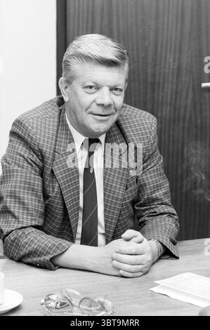 Herr Greymans KNVB Royal Dutch Football Association K.N.V.B., Whizgle News, Dutch Desk, Niederlande, 1950 - 2000 am 21.08.1986. Diese Themen sind in der Abbildung dargestellt. In einem gut beleuchteten Innenbereich sitzt ein Mann an einem Holztisch und strahlt eine Atmosphäre der Ruhe aus. Er trägt einen karierten Anzug mit Grau- und Schwarztönen, ergänzt durch ein knackiges, weißes Hemd und eine Krawatte, die ein dezentes Muster zeigt, wahrscheinlich in dunkleren Tönen. Sein Haar ist sauber zurückgekämmt, es entfaltet eine leichte Welle, und er trägt einen freundlichen Ausdruck mit einem sanften Lächeln. Der Hintergrund ist eine tiefe, reiche Holzverkleidung, Stockfoto
