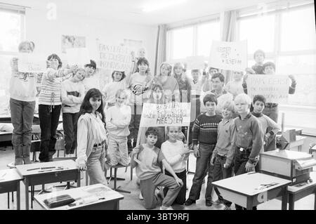 Schüleraktion „Master Must Stay“, Whizgle News, Dutch Desk, Niederlande, 1950 - 2000 am 24-05-1983. Dies sind die Elemente im Bild. In einem hellen, lichtdurchfluteten Klassenzimmer steht eine Gruppe von Kindern mit Begeisterung und Energie. Die Szene vermittelt ein starkes Gefühl von Einheit und Zweck, während sie sich versammeln und Zeichen hochhalten, die ihre Botschaft ausdrücken. Die Schüler tragen eine Mischung aus lässiger Kleidung, die typisch für eine Schulumgebung ist und eine Vielzahl von Mustern und Farben aufweist; einige tragen Streifen, andere tragen einfarbige Farben. Ihre Ausdrücke reichen von Entschlossenheit bis e Stockfoto