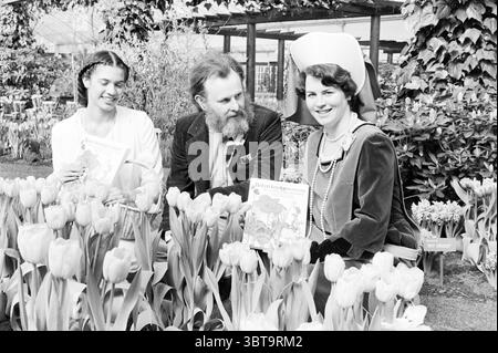 Präsentation von Zwiebeln- und Knollenpflanzen Spectrum Keukenhof Lisse Spectrum Lisse, Whizgle News, Dutch Desk, Niederlande, 1950 - 2000 am 25-03-1982. Dies sind die Elemente im Bild. Die Szene fängt einen Moment in einem lebendigen Garten ein, der reich an blühenden Tulpen in verschiedenen Tönen ist, wie zartem Rosa, Gelb und cremigem weiß. Im Vordergrund bilden die Blumen einen üppigen, farbenfrohen Teppich, der die lebhafte Atmosphäre unterstreicht. Drei Individuen stehen im Mittelpunkt der Komposition. Links sitzt eine Frau mit dunklen, geflochtenen Haaren, deren nachdenklicher Ausdruck sich von ihrem lebhaften Su abhebt Stockfoto