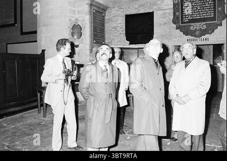 Bischof Bomers besucht St. Bavo Churches Roman Catholic Church, Whizgle News, Dutch Desk, Niederlande, 1950 - 2000 am 20.05.1984. Diese Themen werden in der Abbildung angezeigt. Die Szene spielt drinnen, innerhalb des weitläufigen Innenraums eines alten Gebäudes, das auf historische Bedeutung hinweist, vielleicht eine Kirche oder ein Museum. Die Wände sind mit dunklen Holzpaneelen verziert, was die feierliche und reflektierende Atmosphäre unterstreicht. Eine Gruppe von Individuen steht im Vordergrund, deren Aufmerksamkeit nach oben gerichtet ist, als ob sie etwas beeindruckendes beobachten, vielleicht eine Wandmalerei oder eine kunstvolle Architektur. Die Kleidung des Volkes Stockfoto