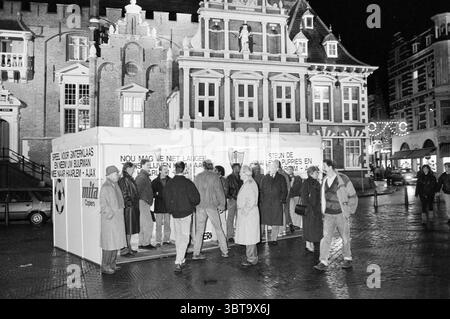 Stehe Haarlem mit Spielern Gr. Market Daycares Football Haarlem Haarlem Grote Markt Niederlande, Whizgle News, Dutch Desk, Niederlande, 1950 - 2000 auf 30-11-1988. Dies sind die Elemente im Bild. Auf einem belebten Stadtplatz versammelt sich eine Gruppe von Einzelpersonen um ein großes, weißes Gebäude, das sich von der umgebenden Architektur abhebt. Das Gebäude dahinter zeigt komplizierte, traditionelle Designs mit einer Mischung aus Stein- und Holzrahmen, mit kunstvollen Giebeln und dekorativen Elementen, die auf seine historische Bedeutung hinweisen. Die Menge, die in Winterkleidung gekleidet ist, zeigt eine Reihe von Schauplätzen Stockfoto