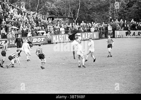 RCH - Velox Football R.C.H., Whizgle News, Dutch Desk, Niederlande, 1950 - 2000 am 15.05.1967. Dies sind die Themen im Bild. Die Szene zeigt einen intensiven Moment während eines Fußballspiels gegen ein grasbewachsenes Feld. Die Spieler tragen überwiegend kontrastierende schwarz-weiß gestreifte Trikots, einige tragen weiße oder helle Trikots. Ihre dynamischen Stellungen vermitteln ein hohes Maß an Aktion und Wettbewerbsgeist, da sie sich in einem entscheidenden Spiel engagieren. In der Mitte der Szene springt ein großer Spieler, wahrscheinlich der Torhüter, in die Luft, mit ausgestreckten Armen, als würde er versuchen, zu katzen Stockfoto