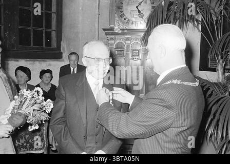 Auszeichnung der Mr. Tierie Awards, Whizgle News, Dutch Desk, Niederlande, 1950 - 2000 am 20-12-1968. Diese Themen werden in der Abbildung angezeigt. Die Szene fängt einen wichtigen Moment ein, wahrscheinlich während einer formellen Veranstaltung oder Zeremonie, der durch ein Gefühl der Feier und Anerkennung gekennzeichnet ist. Im Vordergrund stehen zwei Männer. Einer trägt einen dunklen Anzug mit einer hellen Krawatte und hat ein breites Lächeln, das ein Gefühl von Freude und Wertschätzung zeigt. Der andere trägt einen Nadelstreifenanzug mit einer Bürokette um den Hals und scheint eine Medaille oder Auszeichnung zu überreichen, was auf einen Moment der Ehre hinweist. Im Hintergrund Stockfoto