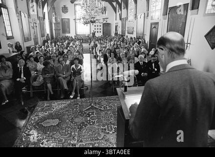 Preisverleihung Landjuweel Haarlem Award Ceremony Theater, Whizgle News, Dutch Desk, Niederlande, 1950 - 2000 am 12-06-1976. Diese Themen werden in der Abbildung angezeigt. Die Szene zeigt eine große Zusammenkunft, die in einem eleganten Raum stattfindet, der von hohen Decken und komplexen architektonischen Details geprägt ist. Die Umgebung ist wahrscheinlich eine Halle oder Kapelle mit großen Fenstern, die mit Buntglas verziert sind, die bunte Muster auf die Elemente im Raum werfen. Ein großer Kronleuchter hängt von der Decke und sorgt für sanftes, warmes Licht und natürliches Licht, das durch die Fenster eindringt. Diese cr Stockfoto
