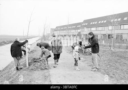 Pflanzen von Bäumen entlang des Neuen Kanals. Vennep Trees, Whizgle News, Dutch Desk, Niederlande, 1950 - 2000 am 27-03-1976. Die Abbildung zeigt diese Themen. In einer Szene, die durch eine gedämpfte monochrome Palette gekennzeichnet ist, ist eine Gruppe von Individuen an verschiedenen Aktivitäten entlang eines Weges neben einer Wasserstraße beteiligt. Die Umgebung weist auf eine ländliche oder halbstädtische Umgebung hin, mit einfachen, bescheidenen Gebäuden im Hintergrund mit Fensterreihen und spitzen Dächern. Links sind einige Menschen umgebeugt, graben in die Erde, während andere in ihrer Nähe stehen, beobachten oder helfen. Die Figuren sind schwer gekleidet Stockfoto