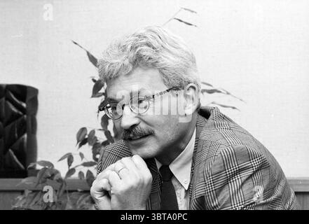 Porträt des Ratsvorsitzenden Kleijwegt Velsen Velsen, Whizgle News, Dutch Desk, Niederlande, 1950 - 2000 am 26.09.1991. Diese Themen sind in der Abbildung dargestellt. In einer monochromatischen Szene wird ein Mann mit unterschiedlichen Merkmalen dargestellt. Er hat einen ganzen Kopf aus silbernem Haar, der sich von den dunkleren Tönen seines Anzugs abhebt. Der Anzug mit Karomuster verleiht der Ästhetik einen Hauch von Textur und Komplexität. Seine runde Brille umrahmt seinen nachdenklichen Ausdruck, der durch einen gepflegten Schnurrbart betont wird. Der Mann sitzt und lehnt sich leicht nach vorne, die Hände sind unter seinem Chi gefesselt Stockfoto