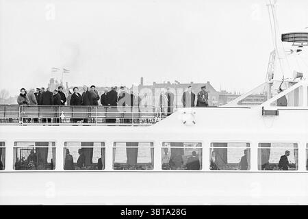 Besuch von Präsident Mexiko in Rotterdam und Verolme Werft. Spido Tour Boot Pieter Calland Rotterdam Veerhaven, Whizgle News, Dutch Desk, Niederlande, 1950 - 2000 im Jahr 1963. Dies sind die Elemente im Bild. Die Szene zeigt ein weißes, modernes Gefäß, das über ein Gewässer gleitet. Das obere Deck ist mit einer Vielzahl von Individuen bevölkert, die alle in Winterkleidung gekleidet sind – schwere Mäntel, Hüte und Tücher – was eine kühle Atmosphäre vermittelt. Die Menge scheint in Gesprächen verwickelt zu sein, einige lehnen sich gegen das Geländer, während andere aufrecht stehen und auf die Aussicht blicken. Im Hintergrund Stockfoto