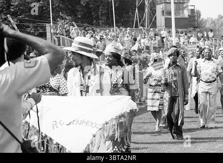 Haarlem - Robin Hood Football Haarlem, Whizgle News, Dutch Desk, Niederlande, 1950 - 2000 am 15-08-1976. Dies sind die Elemente im Bild. Die Szene fängt eine lebendige und energiegeladene Prozession ein, wahrscheinlich während eines kulturellen Ereignisses oder Festivals. Im Vordergrund steht eine Gruppe von Personen, die jeweils in farbenfroher Kleidung gehalten sind, die ein reiches Erbe widerspiegelt. Eine Figur zeichnet sich durch einen großen Strohhut aus, während eine andere ein aufwendig gestaltetes Outfit aus gemustertem Stoff trägt. Die Atmosphäre ist lebendig mit einem Gefühl der Feier, da die Teilnehmer anscheinend lebhaft sind Stockfoto