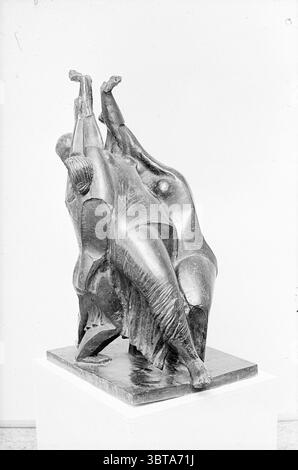 Statue auf Sockel, Whizgle News, Dutch Desk, Niederlande, 1950 - 2000. Diese Themen sind in der Abbildung dargestellt. Die Szene zeigt eine markante Bronzeskulptur, die zwei Figuren in einer dynamischen und ineinander verflochtenen Pose darstellt. Die Figuren werden stilisiert dargestellt und zeigen glatte Kurven und kantige Elemente, die ein Gefühl von Bewegung und Energie erzeugen. Ihre Körper sind anmutig verzerrt, was auf eine emotionale Verbindung hindeutet und möglicherweise Themen wie Kampf, Einheit oder Feier vermittelt. Die Oberfläche der Skulptur ist strukturiert und fängt Licht und Schatten auf eine Weise ein, die ihre drei Dimensionen verstärkt Stockfoto
