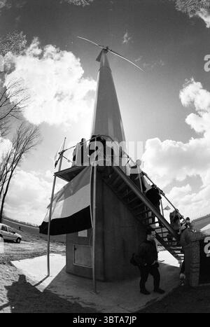 Zweite Windmühle A44 Nieuw-Vennep Nieuw-Vennep, Whizgle News, Dutch Desk, Niederlande, 1950 - 2000 am 11-04-1997. Dies sind die Elemente im Bild. Die Szene zeigt eine moderne Windkraftanlage mit einer hohen, schlanken Turbinenstruktur mit einer spitzen Oberseite und langen, in den Himmel ragenden Schaufeln. Die metallische Oberfläche der Turbine leuchtet bei hellem Tageslicht und bildet einen starken Kontrast zu einem dramatischen Himmel voller flauschiger, weißer Wolken, die über eine leuchtend blaue Kulisse verstreut sind. Das Sonnenlicht erzeugt einen kontraststarken Effekt, erzeugt starke Schatten und beleuchtet verschiedene Elemente Stockfoto