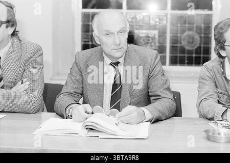 Mitglied des elternrates in Haarlem Haarlem Niederlande, Whizgle News, Dutch Desk, Niederlande, 1950 - 2000 am 27.09.1977. Dies sind die Themen im Bild. In einem gut beleuchteten Raum sitzen drei Personen an einem langen Tisch. Die Umgebung erscheint formell und professionell, wahrscheinlich Teil einer Besprechung oder Diskussion. Die Oberfläche des Tisches ist überfüllt mit Papieren und möglicherweise einigen Gegenständen, die auf laufende Arbeiten oder Diskussionen hinweisen. Die zentrale Figur, die ein Gefühl von Autorität und Konzentration ausstrahlt, trägt einen maßgeschneiderten, hellen Anzug. Er hält eine Brille in den Händen, Finger gemächlich Stockfoto