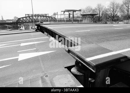 Prinsenbrug defekt + Verkehrsstau in Waarderpolder Brücken Brückenbau beschäftigt Haarlem Oudeweg Niederlande, Whizgle News, Dutch Desk, Niederlande, 1950 - 2000 am 03-05-1989. Die Abbildung zeigt diese Themen. In dieser Szene wird eine breite und breite Straße dargestellt, die durch eine ausgeprägte Schwarz-weiß-Farbpalette gekennzeichnet ist, die eine starke, dramatische Qualität verleiht. Der Vordergrund zeigt einen Abschnitt der Straße, der höher oder leicht voneinander getrennt zu sein scheint, was auf eine verstellbare oder bewegliche Struktur hindeutet, die typischerweise bei Brückenkonstruktionen zu finden ist. Die Straßenoberfläche ist strukturiert und mit sichtbarer Markierung versehen Stockfoto