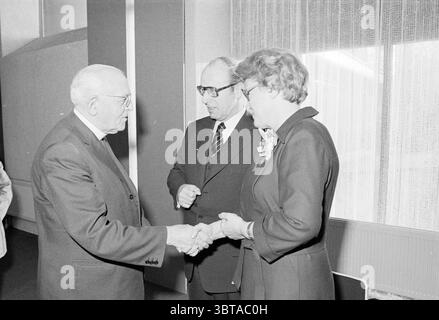 Abschiedsempfang Dr. van. Rhein Doctors Reception, Whizgle News, Dutch Desk, Niederlande, 1950 - 2000 am 10-12-1976. Die Abbildung zeigt diese Themen. In einer formellen Umgebung sind drei Personen in einem Moment der Interaktion engagiert. Die Hauptfigur, ein älterer Mann mit silbernen Haaren und Brillen, steht links. Er zeigt einen würdevollen Ausdruck und trägt einen dunklen Anzug. Seine Hand wird in einem Handschlag gestreckt, was auf eine Geste des Willkommens oder der Zustimmung hindeutet. Zu seiner Rechten steht ein anderer Mann, ebenfalls in einem dunklen Anzug und einer Brille gekleidet, der mitten im Gespräch zu sein scheint. Er bleibt leicht tur Stockfoto