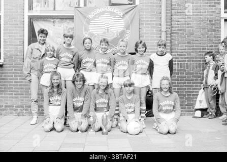 Mädchen-Team Bosbeekschool Santpoort Santpoort, Whizgle News, Dutch Desk, Niederlande, 1950 - 2000 am 11-05-1990. Diese Themen werden in der Abbildung angezeigt. Die Szene zeigt eine Zusammenkunft einer Jugendsportmannschaft, die überwiegend aus Kindern in passenden Uniformen besteht, die in zwei Reihen stehen. Die erste Reihe zeigt Mädchen in aufeinander abgestimmten Outfits mit einigen sportlichen Haarbändern und fröhlichen Ausdrucksformen. Ihre Shorts sind hell und ergänzen ihre lebhaften Langarm-Trikots mit einem markanten Logo. Hinter ihnen zeigen die Jungs in der hinteren Reihe eine Mischung von Ausdrucksformen, von selbstbewusst bis hin zu Stockfoto