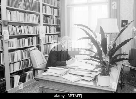 Bischof Bomers of Haarlem Roman Catholic Church Haarlem the Netherlands, Whizgle News, Dutch Desk, Niederlande, 1950 - 2000 am 03-09-1984. Dies sind die Elemente im Bild. In einer Inneneinrichtung, die von dem warmen Licht des natürlichen Lichtes erfüllt ist, das durch große Fenster filtert, sitzt ein älterer Mann an einem Eichenpult, tief in seine Arbeit vertieft. Er trägt ein dunkles, formelles Outfit, das auf ein wissenschaftliches Verhalten hindeutet. Sein Haar ist grau und spärlich, und er scheint in nachdenklicher Konzentration zu sein, mit einer Hand hält er einen Bleistift über Blätter, die über den Schreibtisch verstreut sind. Um ihn herum, eine reiche Darstellung von Stockfoto