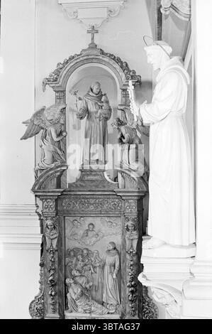 Bilder der Groenmarkt-Kirche römisch-katholische Kirchen R.C.-Kirchen Haarlem Nieuwe Groenmarkt Niederlande, Whizgle News, Dutch Desk, Niederlande, 1950 - 2000 am 22-10-1969. Dies sind die Elemente im Bild. Die Szene zeigt einen detailreichen Altar mit einer aufwendigen Anordnung von Statuen und kunstvollen Schnitzereien. Im Zentrum der Komposition steht eine prominente Figur des Heiligen Franziskus, die in einer stehenden Pose mit heiterem Ausdruck dargestellt ist und ein Kreuz hält. Er steht geschützt unter einem kunstvollen Bogen, der der Szene ein Gefühl von Pracht verleiht. Der Heilige Franziskus flankiert zwei Engelsfiguren Stockfoto