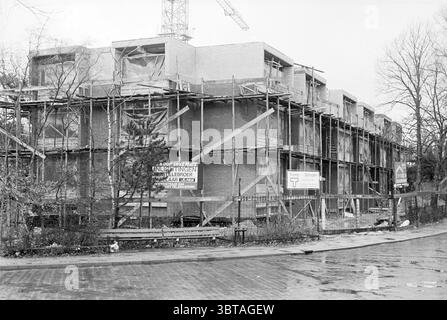 Neubau Longwood Willem de Zwijgerlaan S'poort Häuser und Hausbau Neubau Santpoort-Zuid Willem de Zwijgerlaan, Whizgle News, Dutch Desk, Niederlande, 1950 - 2000 am 02-12-1975. Die Abbildung zeigt diese Themen. Die Szene zeigt eine aktive Baustelle, die sich durch ihre unvollendete Struktur auszeichnet. Das mit Gerüsten umrahmte Gebäude zeigt freiliegende Ziegelsteine und Materialien, die eine robuste und zugleich rohe Ästhetik vermuten lassen. Die Architektur deutet auf ein modernes Design hin, das eindeutig für den privaten oder gewerblichen Gebrauch bestimmt ist. Um das Hauptgebäude herum ist das Gerüst intri Stockfoto
