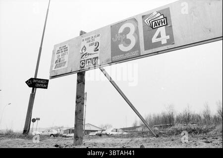 Wahlzeichen O R Hochöfen Hochöfen, Whizgle News, Dutch Desk, Niederlande, 1950 - 2000 am 07-04-1986. Diese Themen sind in der Abbildung dargestellt. Die Szene zeigt eine verwitterte Holzstruktur mit mehreren Schildern. Die Schilder sind unterschiedlich groß und haben eine Mischung aus Grafiken und Logos, die wahrscheinlich verschiedene Organisationen oder Botschaften repräsentieren. Einige Schilder haben fettgedruckte Zahlen und Buchstaben, während andere mit komplizierten Designs oder Symbolen versehen sind, die auf eine Beteiligung an der Gemeinschaft oder eine Wegbeschreibung hinweisen. Die Farbpalette ist stummgeschaltet, wobei Grautöne, Schwarz und weiß dominieren und ein Übermaß reflektieren Stockfoto
