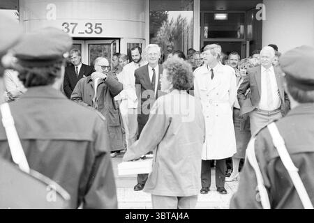 Eröffnung des Gebäudes der Steuerbehörde Hoofddorp the Netherlands, Whizgle News, Dutch Desk, Niederlande, 1950 - 2000 am 06-09-1990. Diese Themen werden in der Abbildung angezeigt. Die Szene fängt einen bedeutenden Moment außerhalb eines modernen Gebäudes mit einem runden Eingang ein, der durch große Glastüren und ein klares, zeitgenössisches Design gekennzeichnet ist. Im Vordergrund steht eine Gruppe von Individuen in dunklen Uniformen in einem Halbkreis, deren ernste Ausdrucksformen mit dem komponierten Verhalten der im Hintergrund stehenden Personen kontrastieren. Der Hintergrund zeigt eine vielfältige Gruppe von Menschen, darunter Männer in Anzügen und Damenkleidern Stockfoto