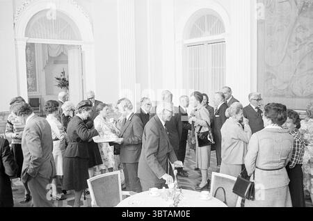 Abschiedsempfang CDK Noord-Holland Mr. F.J. Kranenburg Haarlem Dreef The Netherlands, Whizgle News, Dutch Desk, Niederlande, 1950 - 2000 am 04-1976. Die Abbildung zeigt diese Themen. Die Szene fängt ein geschäftiges Indoor-Treffen ein, wahrscheinlich ein formelles Ereignis, das durch eine vielfältige Gruppe von Teilnehmern gekennzeichnet ist, die sich mit Gesprächen und Kontakten beschäftigen. Die Einrichtung verfügt über elegante architektonische Elemente, mit hohen, weißen Säulen und großen Fenstern, die weiches, diffuses Licht hereinströmen lassen und eine warme und einladende Atmosphäre schaffen. Die Menschen tragen eine Mischung aus formeller und halbformaler Kleidung. Viele Männer sind dabei Stockfoto