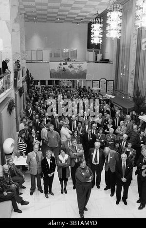 Neujahrsempfang Velsen, Whizgle News, Dutch Desk, Niederlande, 1950 - 2000 am 02-01-1991. Das Bild enthält diese Themen. Die Szene ist gefüllt mit einer großen Menschenmenge, die sich in einem geräumigen, gut beleuchteten Saal versammelt, der sich durch eine hohe Decke und große Fenster auszeichnet, die weiches, diffuses Licht hereinlassen. Die Wände sind in einer Mischung aus hellen Farben und glänzenden Materialien gehalten, was zu einer eleganten und dennoch lebhaften Atmosphäre beiträgt. Im Vordergrund steht eine vielfältige Gruppe von Teilnehmern, die formelle und halbformale Kleidung tragen. Männer in Anzügen und Krawatten mischen sich mit Frauen in Kleidern und Blusen, Ma Stockfoto