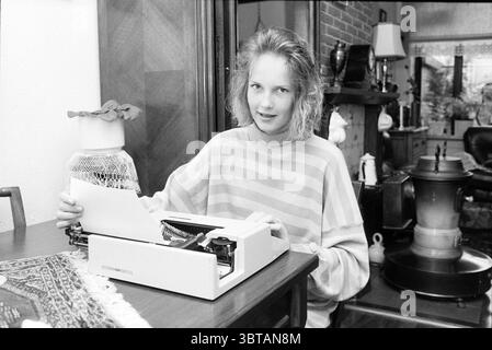 Ester Lammers Exam Kandidat Exam, Whizgle News, Dutch Desk, Niederlande, 1950 - 2000 am 22-07-1988. Dies sind die Elemente im Bild. Die Szene zeigt eine junge Frau, die an einem Holztisch sitzt und auf einer Schreibmaschine schreibt. Sie hat leicht zerzauste Haare und trägt einen gestreiften Pullover, der einen weichen Kontrast zum Hintergrund erzeugt. Die Streifen wechseln zwischen hellen und dunklen Tönen ab und verleihen ihrem Erscheinungsbild einen lässigen, aber stilvollen Touch. Die Schreibmaschine, ein klassisches Modell, steht prominent auf dem Tisch, ihr elegantes weißes Gehäuse steht im Kontrast zum Reichtum des Holzes. Verstreut A Stockfoto