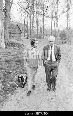 Bericht über die Burg. Cremers Vilsteren Mayors, Whizgle News, Dutch Desk, Niederlande, 1950 - 2000 am 03-05-1969. Die Abbildung zeigt diese Themen. In einer ruhigen Umgebung im Freien gehen zwei Personen Seite an Seite auf einem unbefestigten Pfad entlang, der gut durchgetreten erscheint und von üppigem grünem Gras umgeben ist. Ein Hund, der einem Spaniel ähnelt, trabt spielerisch neben ihnen und verleiht der Szene ein Gefühl von Lebendigkeit. Beide sind elegant gekleidet; die Frau trägt eine maßgeschneiderte, helle Jacke und einen knielangen Rock, ergänzt durch einen zarten Schal, während der Mann mit einem gemusterten Blazer über einem Hemd mit Kragen bekleidet ist Stockfoto