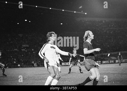 Football Amsterdam 701 Anderlecht - Leeds United Football, Whizgle News, Dutch Desk, Niederlande, 1950 - 2000 am 06-08-1976. Die Abbildung zeigt diese Themen. Die Szene fängt während eines Abendspiels einen dynamischen Moment auf einem Fußballfeld ein. Die Atmosphäre ist voller Energie, während die Spieler in Aktion intensive Konzentration und Wettkampfgeist zeigen. Im Vordergrund stehen sich zwei Athleten gegenüber: Einer trägt ein weißes Trikot, der andere trägt ein dunkles Trikot. Der Spieler in weiß scheint in der Mitte des Spiels an einem Manöver teilzunehmen, das möglicherweise ein Signal oder eine Reaktion auf ein Spiel gibt. Sein hai Stockfoto