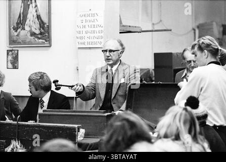 KLM Versteigerung von verlorenen Immobilien in Amsterdam KLM Auktion Amsterdam Niederlande, Whizgle News, Dutch Desk, Niederlande, 1950 - 2000 am 17.12.1980. Die Abbildung zeigt diese Themen. Die Szene zeigt eine geschäftige Auktion, in der eine Reihe von Personen verschiedene Aktivitäten ausüben. An der Spitze steht ein Mann selbstbewusst auf einem hölzernen Podium, mit einem Hammer in einer Hand. Er trägt einen formellen Anzug, sein Ausdruck ernst, aber bestimmt, was seine Rolle als Auktionator andeutet. Sein Haar ist leicht, und er trägt eine Brille, was zu einem professionellen Aussehen beiträgt. Er sitzt links, ein Paar Stockfoto