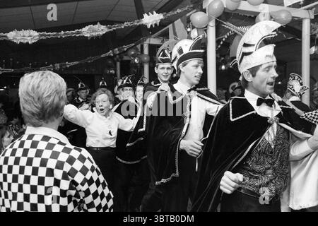 Karneval Three House Party Driehuis, Whizgle News, Dutch Desk, Niederlande, 1950 - 2000 am 18-01-1991. Dies sind die Themen im Bild. Eine lebhafte Szene entfaltet sich in einem festlichen Saal, der mit farbenfrohen Dekorationen geschmückt ist, die auf eine festliche Atmosphäre hinweisen. Der Raum ist voller Ballons und Streamer, die eine verspielte und lebendige Kulisse schaffen. Im Vordergrund stehen mehrere Personen, die in aufwendigen Kostümen gekleidet sind, die auf ein kulturelles oder festliches Thema hinweisen. Ihre Outfits sind reich an Details und kombinieren Elemente wie Samt und glänzende Stoffe mit komplizierten Designs und Stockfoto