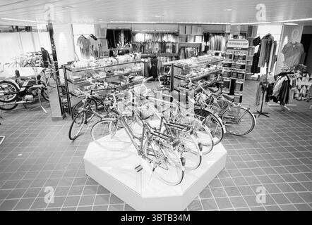 Int. Neuer Fahrradladen Verdonschot Radwege Radfahrer Heemstede Niederlande, Whizgle News, Dutch Desk, Niederlande, 1950 - 2000 am 27-02-1989. Diese Themen werden in der Abbildung angezeigt. Die Szene spielt in einer geräumigen Einzelhandelsumgebung mit modernem, organisiertem Layout. Der Bodenbelag ist mit einem Gittermuster aus dunklen Fliesen versehen, die einen deutlichen Kontrast zu den helleren Tönen des umgebenden Innenraums bilden. Eine zentrale Ausstellung zeigt eine Sammlung von Fahrrädern, die ordentlich auf einer erhöhten Plattform angeordnet sind und mit ihren vielfältigen Designs und leuchtenden Farben das Auge auf sich ziehen. Um die Fahrräder herum, sh Stockfoto